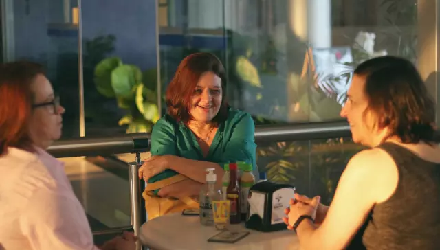 Friends laughing at a table in the evening